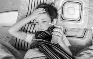 black and white picture of a boy in bed with an inhaler