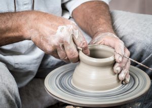 person's hands making pottery
