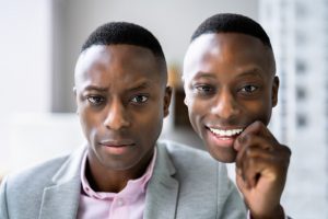 african american man upset holding a copy of his face smiling