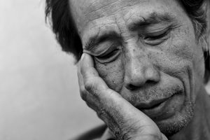 black and white picture of an asian man looking down and tired