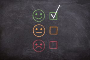 happy sad and medium faces on a board with a check mark nextto happy