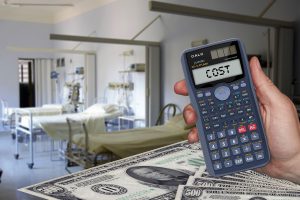 hand holding a calculator with the word cost on it and a hospital room in the background