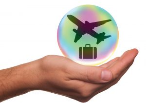 a hand with a bubble over it with an airplane and suitcase in the bubble