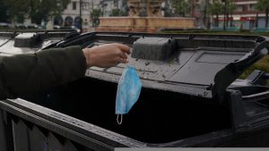hand throwing a mask into a trash can