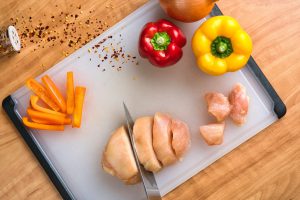 chicken being cut up with peppers next to it