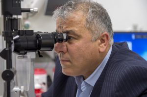 older man looking through an eye doctor's machine