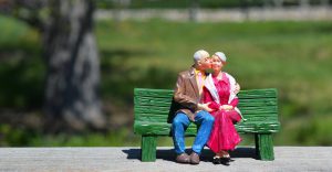 figure of an older man and woman sitting on a bench with the man kissing the woman on the cheek