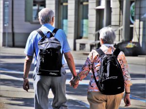 older couple holding hands with bookbags on