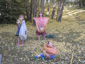 kids with bags of leaves and a rake on the ground