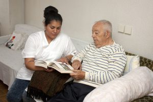 woman sitting next to an older man showing him things in a book