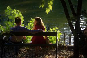 a man and woman sitting on a bench talking