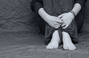 black and white picture of a person sitting down holding their shins