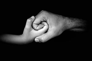 adult hand holding a child's hand