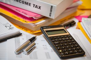 calculator next to income tax book and a pen and papers