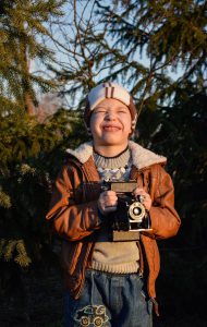 kid holding a camera smiling