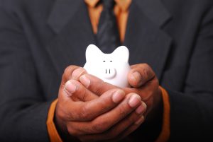 person in a suit holding a white piggy bank
