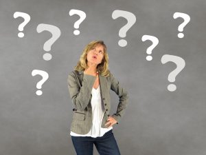 woman looking up with question marks all around her