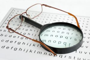 eyeglasses and magnifying glass on paper filled with letters