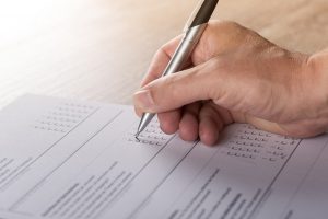 hand holding a pen and filling out a survey