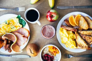 plates of breakfast with eggs oranges meat and coffee on a table