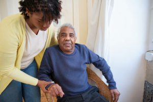 image of a younger woman helping an elderly man out of a chair
