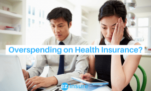 overspending on health insurance? text overlaying image of a couple looking at their finances and stressed out